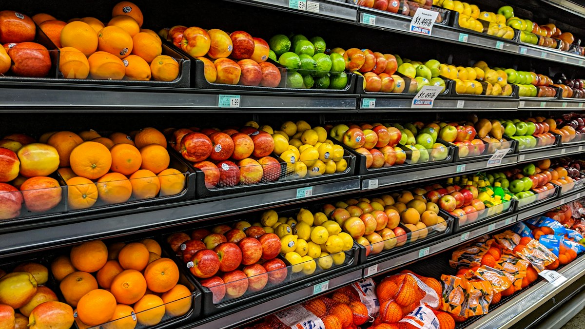 Grocery store shelves of oranges, apples, lemons and limes