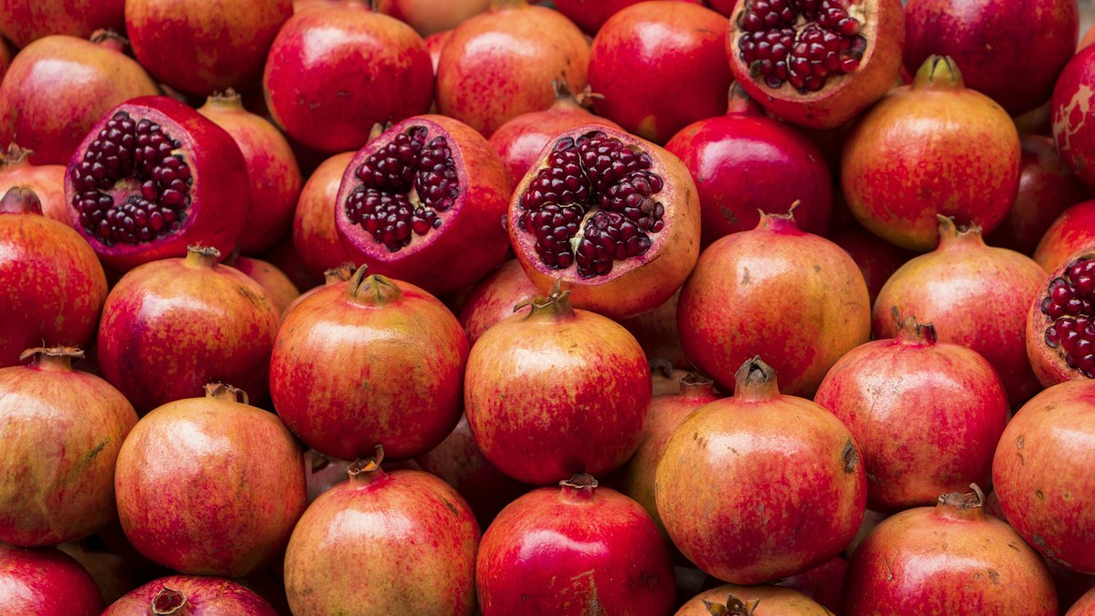 Whole and halved pomegranates showing red seeds